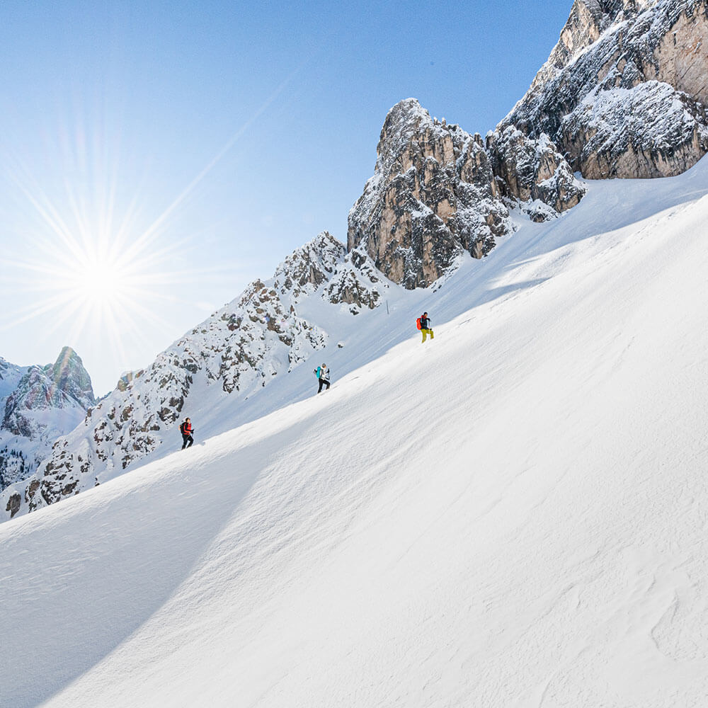 Drei Skitourengeher im Neuschnee unter blauem Himmel - Zin Park Residence